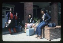Students in front of a dorm with luggage
